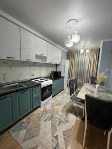 a kitchen with green cabinets and a table with chairs at Комфортные апартаменты в ЖК Наурыз парк in Shymkent