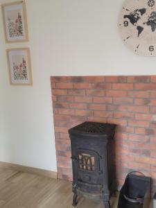 una chimenea de ladrillo con un reloj en la pared en Domek na lipowym wzgórzu, en Długie