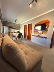 a living room with a couch and a tv on the wall at Bangalô Miramar Maragogi in Maragogi