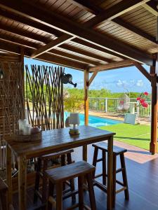 einen Holztisch und Stühle auf einer Terrasse mit einem Pool in der Unterkunft Villa Iséa - Piscine privée & Terrasse Vue Mer in Le Gosier + 40 Fotos