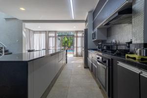 a large kitchen with black counter tops and appliances at Alto Padrão 5 Stes +1 apoio Piscina quente+Jacuzzi in Praia Guaratuba