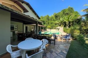 a patio with a table and chairs and a pool at Fantastica casa proxima do mar! in Praia Guaratuba