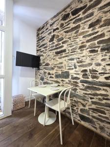 a table and chairs in front of a stone wall at Estudio Casco Histórico Betanzos in Betanzos