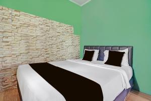 a bedroom with a large bed with a brick wall at Collection O Subang near Ciater Subang formerly Orchid Villa Ciater in Ciater