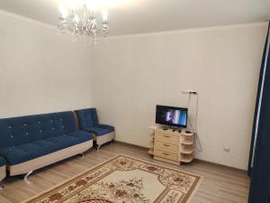 a living room with a blue couch and a tv at Светлая теплая двухкомнатная квартира на Юго-Востоке in Karagandy