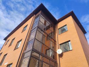 a brick building with glass windows on the side of it at Светлая теплая двухкомнатная квартира на Юго-Востоке in Karagandy