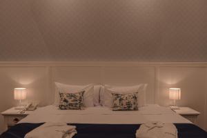 a white bed with two pillows and two lamps at Parc Royale Suites Hotel in Cuenca