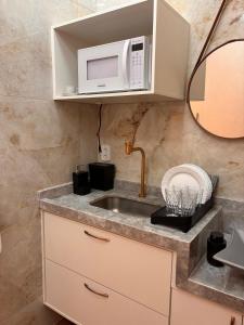 eine Küche mit Spüle und Mikrowelle in der Unterkunft Ste. 6 Premium na quadra da Praia do Forte in Škorak