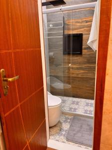 ein Badezimmer mit Toilette und Glasduschtür in der Unterkunft Ste. 6 Premium na quadra da Praia do Forte in Škorak + 5 Fotos