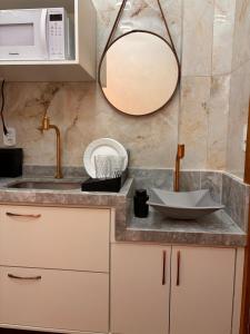 eine Küchentheke mit einem Waschbecken und einem Spiegel in der Unterkunft Ste. 6 Premium na quadra da Praia do Forte in Škorak