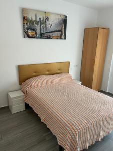 a bedroom with a bed with a striped bedspread at La Ferroviaria - Pequeña Suite De 1 Dormitorio Con Salón y Office más Baño Privado - Prohibido Fumar- Sin Ascensor- in Zaragoza