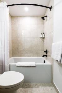 un bagno con una vasca bianca e un water di Aurora Lite - Brand new suite with private entrance a Canmore