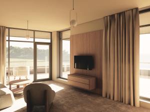 a living room with a tv and a chair at Hotel Princeps in Sátoraljaújhely