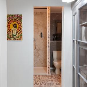a bathroom with a toilet and a painting on the wall at Le Lodge Arthur Appartement 8 personnes in Barraux