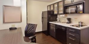 Una cocina con un refrigerador negro y una silla. en Sonesta Simply Suites Knoxville, en Knoxville