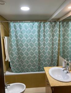 a bathroom with two sinks and a shower curtain at Tróia Resort - Paradise in Troia