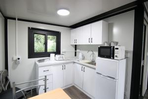 a kitchen with white cabinets and a sink and a microwave at Sunset Retreat Cabin, Hot Tub & Garden views in Portglenone