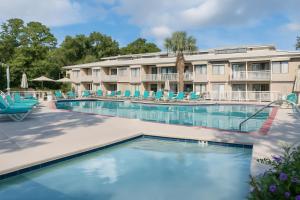 a pool at a resort with blue chairs and a building at Players Club Resort in Hilton Head Island