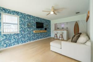 een woonkamer met een witte bank en een plafondventilator bij Lighthouse Point Poolside Retreat in Floresta Estates