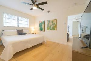 een witte slaapkamer met een bed en een plafondventilator bij Lighthouse Point Poolside Retreat in Floresta Estates +16 foto's
