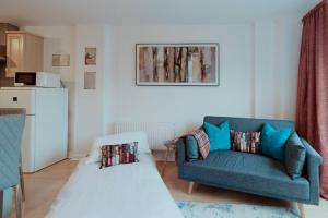 a living room with a blue couch and a table at The Diickens Den - Stylish Rochester 1BR Flat - Sleeps 4 - Walk to High St, Castle & Station with Secured Parking - Contractor - Friendly and Ideal for Long Stays in Rochester