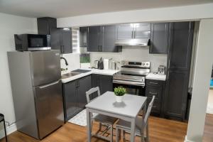 a kitchen with stainless steel appliances and a table with chairs at Studio Apartment A - Full Kitchen - Cozy and Modern in Brampton
