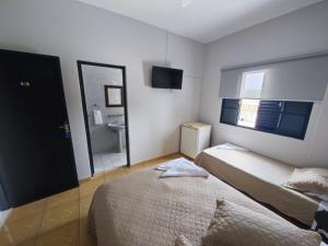 a small bedroom with two beds and a mirror at Chicon's Restaurante e Pousada in Igaratá