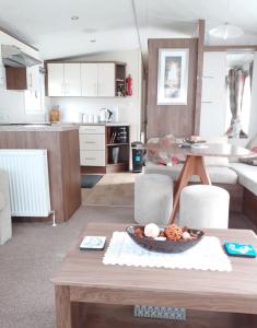 a living room with a table with a bowl of food at Modern 2017 model Delta Sienna static caravan in Clarach Bay in Aberystwyth