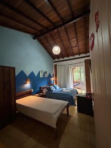 um quarto com paredes azuis, uma cama e uma janela em Pousada Encantos do Mar em Arraial d'Ajuda