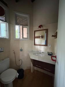um banheiro com uma pia, um vaso sanitário e um espelho em Pousada Encantos do Mar em Arraial d'Ajuda