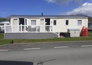 a white house with a porch and a street at Modern 2017 model Delta Sienna static caravan in Clarach Bay in Aberystwyth