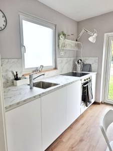 Una cocina blanca con fregadero y ventana. en Ferienhaus Lyś, en Lauta