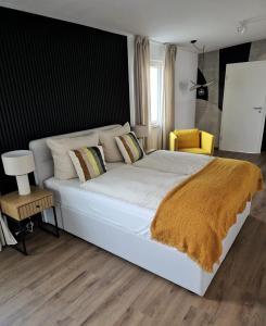 a bedroom with a large white bed with a yellow chair at Ferienhaus Lyś in Lauta