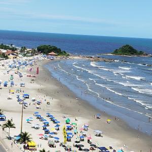 a beach with many people and umbrellas and the ocean at Frente para Mar de água cristalinas in Itanhaém