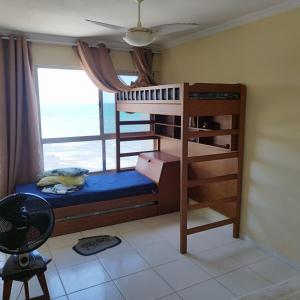 a bedroom with two bunk beds and a window at Frente para Mar de água cristalinas in Itanhaém