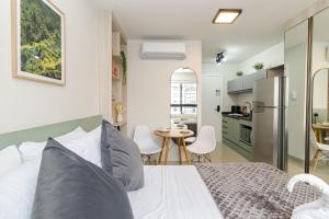 a bedroom with a white bed and a kitchen at MUV Residence - Centro | Gonzaga Stays in Curitiba