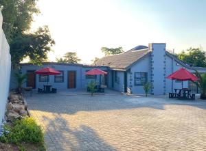 a blue building with red umbrellas and a patio at The Palms Guest House in Johannesburg