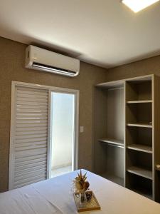 a bedroom with a white bed with a window and a fan at Flat Holanda Piscina e Conforto in Olímpia