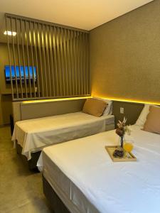 a hotel room with two beds and a window at Flat Holanda Piscina e Conforto in Olímpia +68 photos