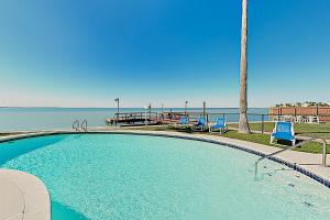 een zwembad met stoelen en de oceaan op de achtergrond bij Marlin Arms Condominiums #9 in South Padre Island