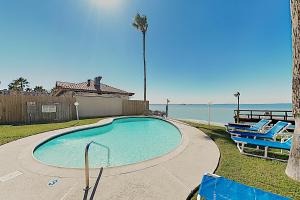 een zwembad met twee stoelen naast de oceaan bij Marlin Arms Condominiums #9 in South Padre Island