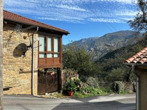 a house with a wooden gate and mountains in the background at Mirador de Proacina - Senda del Oso 