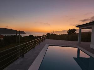 a swimming pool with a sunset in the background at Cantinho do alto in Porto Judeu