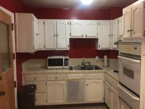 Una cocina con gabinetes blancos, un fregadero y un microondas. en Affordable Rooms in RV Trailer, en Los Ángeles