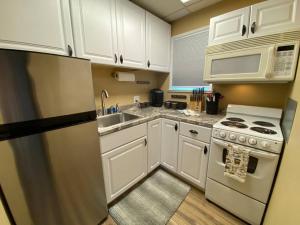 a kitchen with white cabinets and a sink and a stove at Coffee studio, walking distance to downtown in Fairbanks