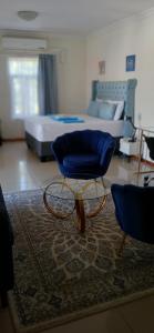 een woonkamer met een blauwe stoel en een bed bij Apartment 505 in Gaborone +38 foto's