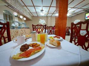 a table with a plate of breakfast foods and orange juice at Hotel Continental Plaza in San Miguel