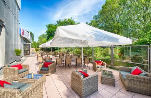 an outdoor patio with chairs and an umbrella at Leonardo Hotel Karlsruhe in Karlsruhe