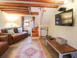 a living room with a couch and a tv at Old Hall Barn 4 in Church Stretton