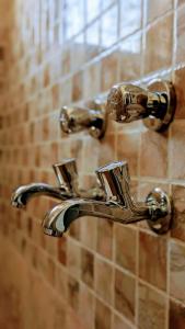 a pair of bronze faucets on a bathroom wall at Nova Nest Stays near Infocity Sai temple in Bhubaneshwar